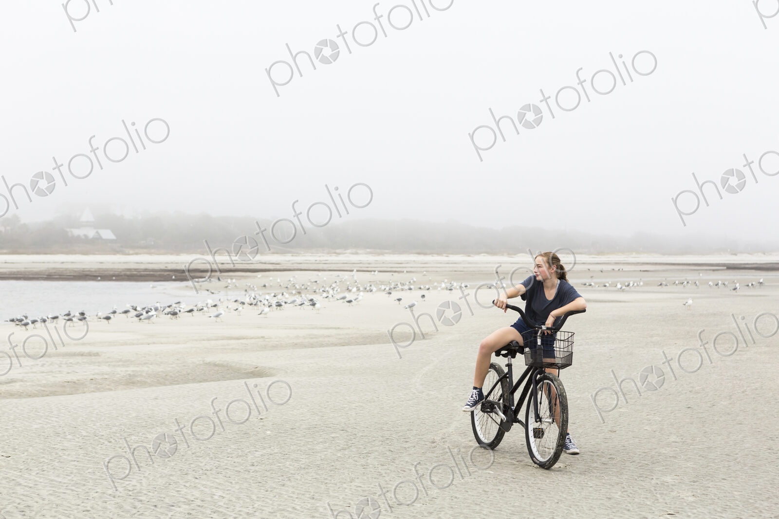 Teen girl biking on sand at the beach, St. Simon’s Island Georgia