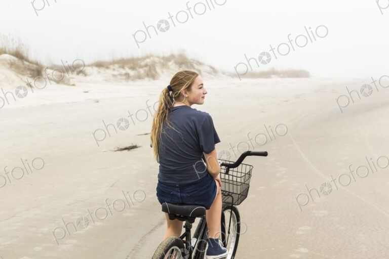 Teen girl biking on sand at the beach, St. Simon's Island Georgia