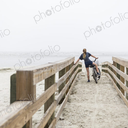Teen girl biking on sandy beach by the ocean, St. Simon's Island, Georgia Teen girl biking on sandy beach by the ocean, St. Simon's Island, Georgia