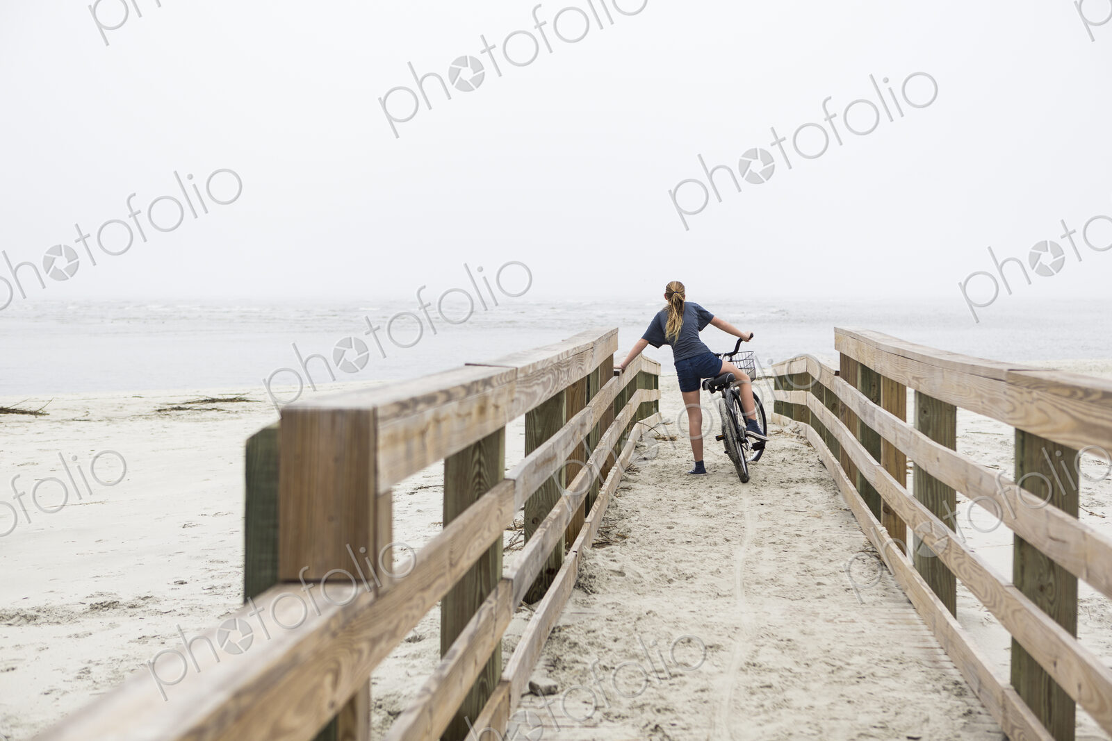 Teen girl biking on sandy beach by the ocean, St. Simon’s Island, Georgia