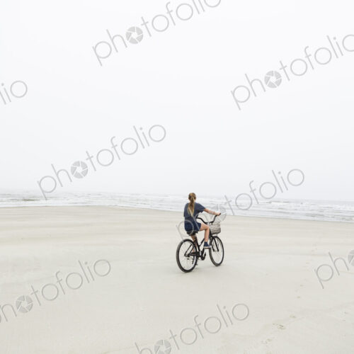 Teen girl biking on sandy beach by the ocean, St. Simon's Island, Georgia