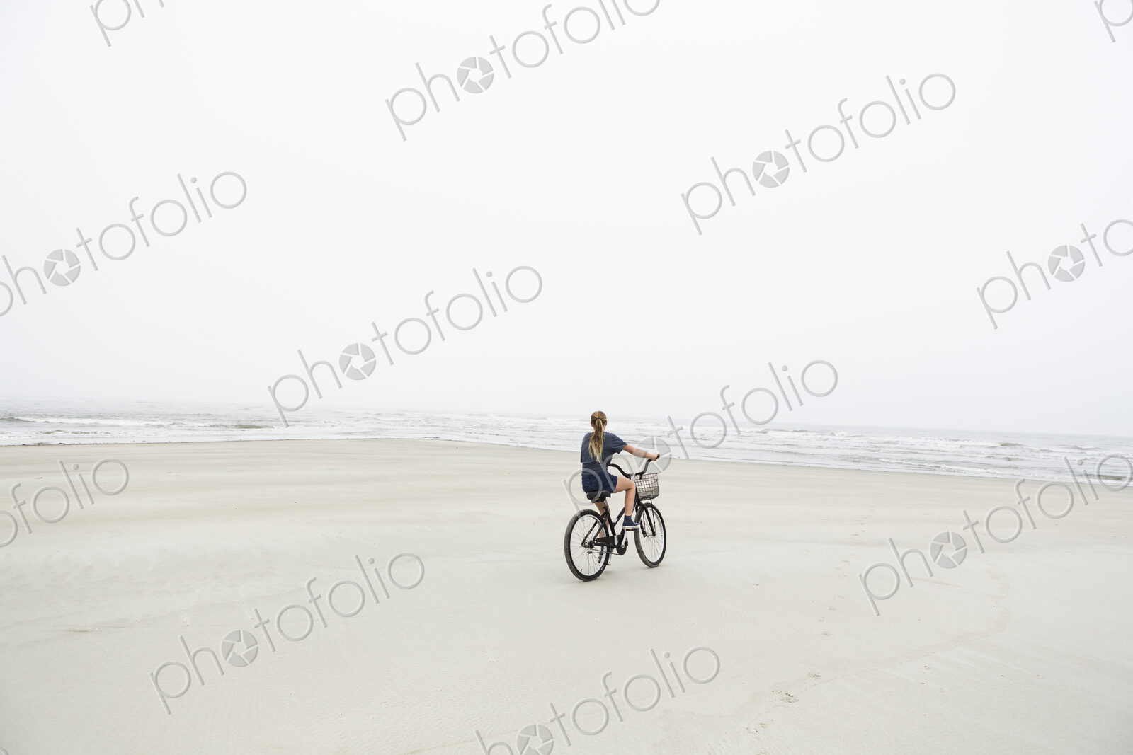 Teen girl biking on sandy beach by the ocean, St. Simon’s Island, Georgia