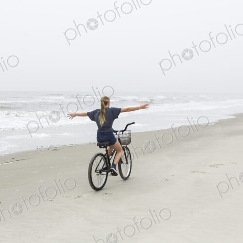 Teen girl biking on sandy beach by the ocean, St. Simon's Island, Georgia Teen girl biking on sandy beach by the ocean, St. Simon's Island, Georgia