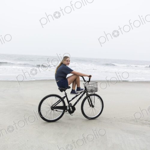 Teen girl biking on sandy beach by the ocean, St. Simon's Island, Georgia