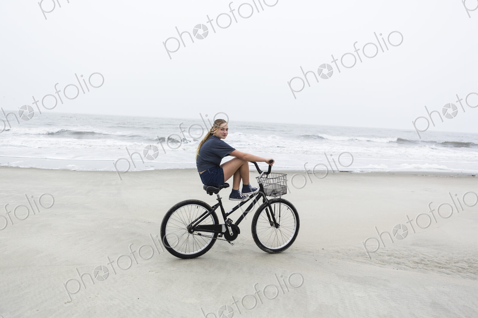 Teen girl biking on sandy beach by the ocean, St. Simon’s Island, Georgia