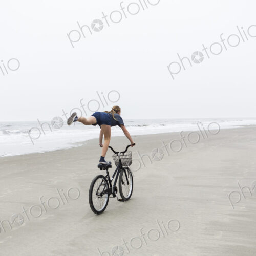 Teen girl biking on sandy beach by the ocean, St. Simon's Island, Georgia