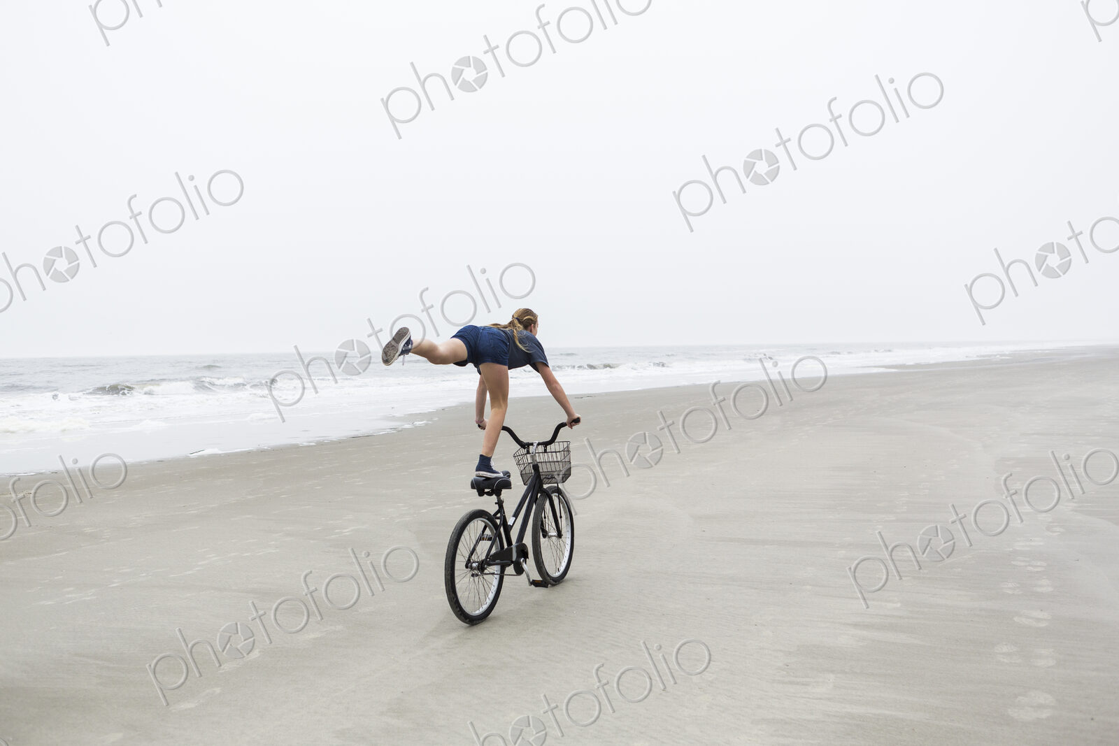 Teen girl biking on sandy beach by the ocean, St. Simon’s Island, Georgia