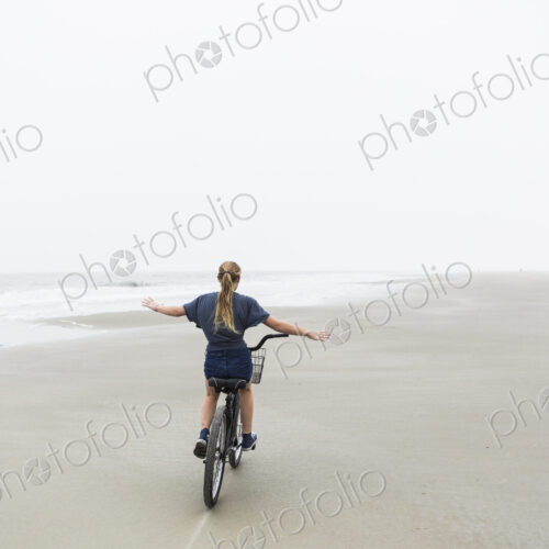 Teen girl biking on sandy beach by the ocean, St. Simon's Island, Georgia Teen girl biking on sandy beach by the ocean, St. Simon's Island, Georgia