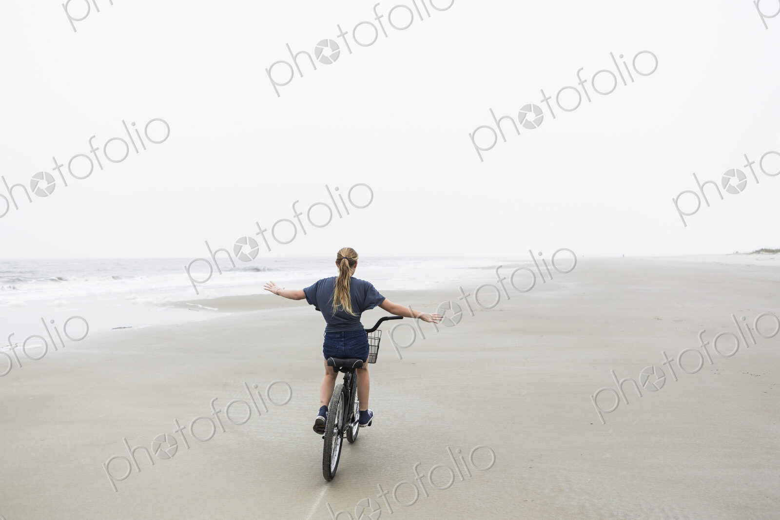 Teen girl biking on sandy beach by the ocean, St. Simon’s Island, Georgia