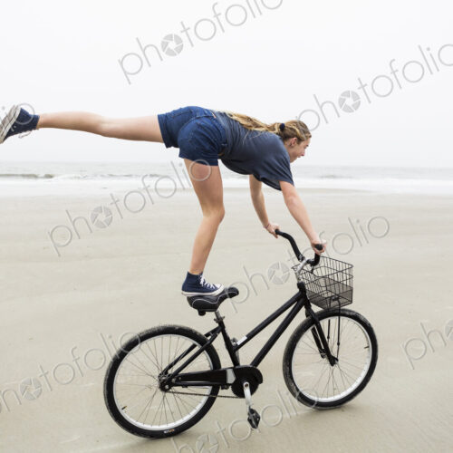 Teen girl biking on sandy beach by the ocean, St. Simon's Island, Georgia Teen girl biking on sandy beach by the ocean, St. Simon's Island, Georgia