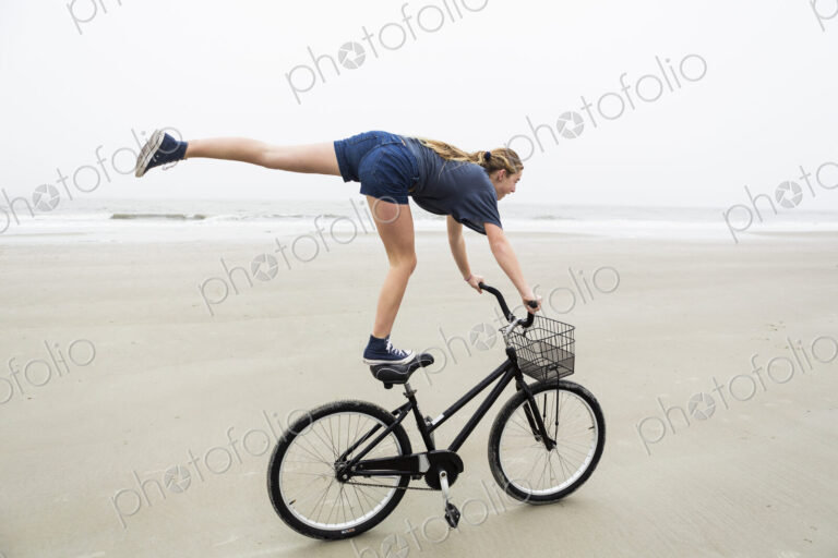 Teen girl biking on sandy beach by the ocean, St. Simon's Island, Georgia