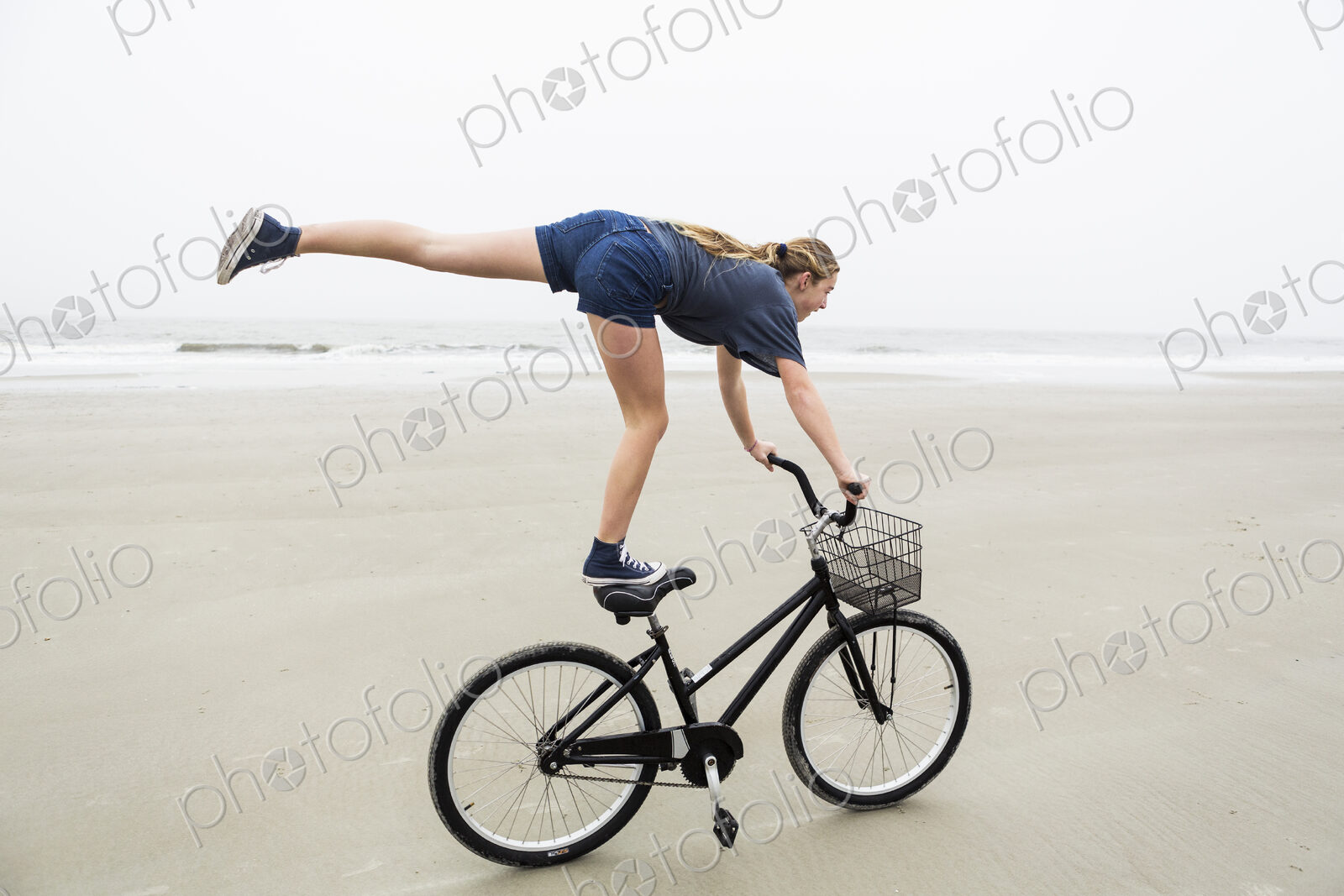 Teen girl biking on sandy beach by the ocean, St. Simon’s Island, Georgia