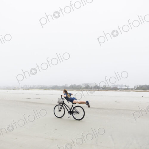 Teen girl biking on sandy beach by the ocean, St. Simon's Island, Georgia Teen girl biking on sandy beach by the ocean, St. Simon's Island, Georgia