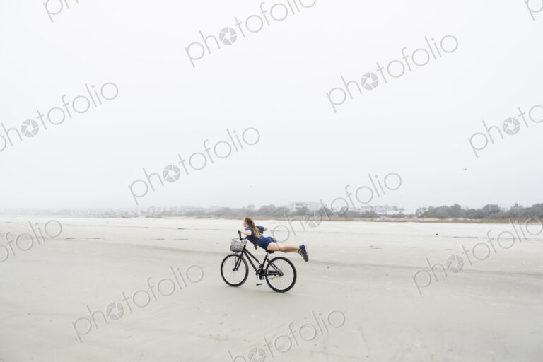 Teen girl biking on sandy beach by the ocean, St. Simon's Island, Georgia