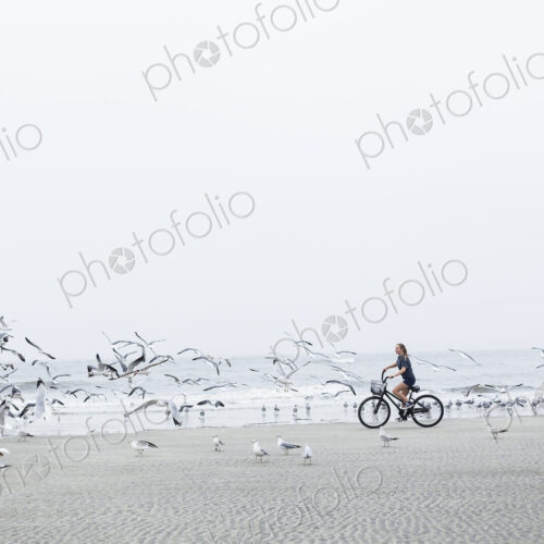 Teen girl biking on sandy beach by the ocean, St. Simon's Island, Georgia Teen girl biking on sandy beach by the ocean, St. Simon's Island, Georgia