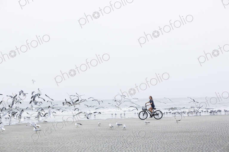 Teen girl biking on sandy beach by the ocean, St. Simon's Island, Georgia