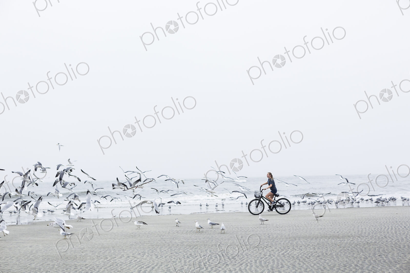 Teen girl biking on sandy beach by the ocean, St. Simon’s Island, Georgia