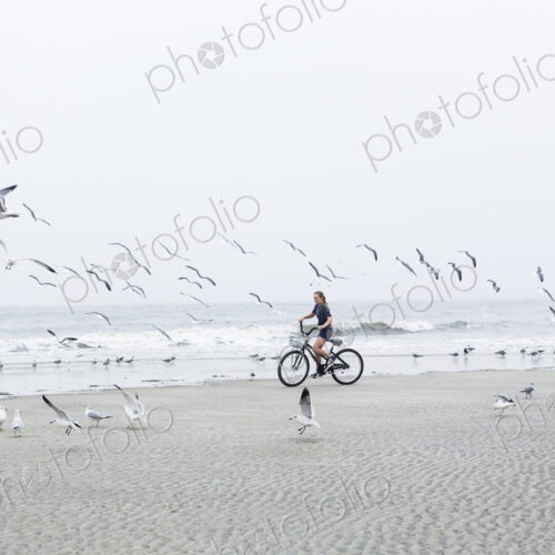 Teen girl biking on sandy beach by the ocean, St. Simon's Island, Georgia Teen girl biking on sandy beach by the ocean, St. Simon's Island, Georgia