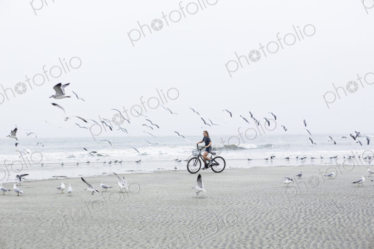 Teen girl biking on sandy beach by the ocean, St. Simon's Island, Georgia