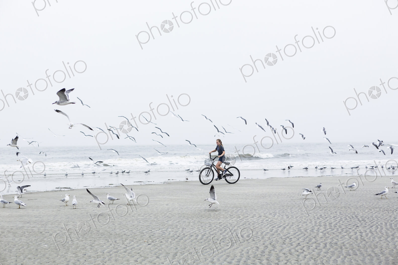 Teen girl biking on sandy beach by the ocean, St. Simon’s Island, Georgia