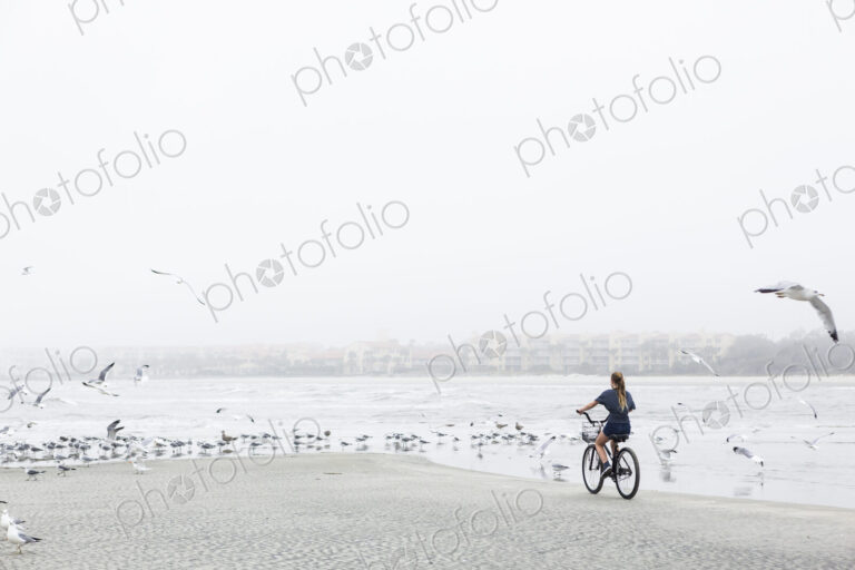Teen girl biking on sandy beach by the ocean, St. Simon's Island, Georgia