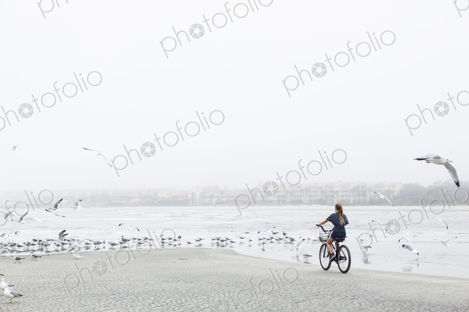 Teen girl biking on sandy beach by the ocean, St. Simon’s Island, Georgia