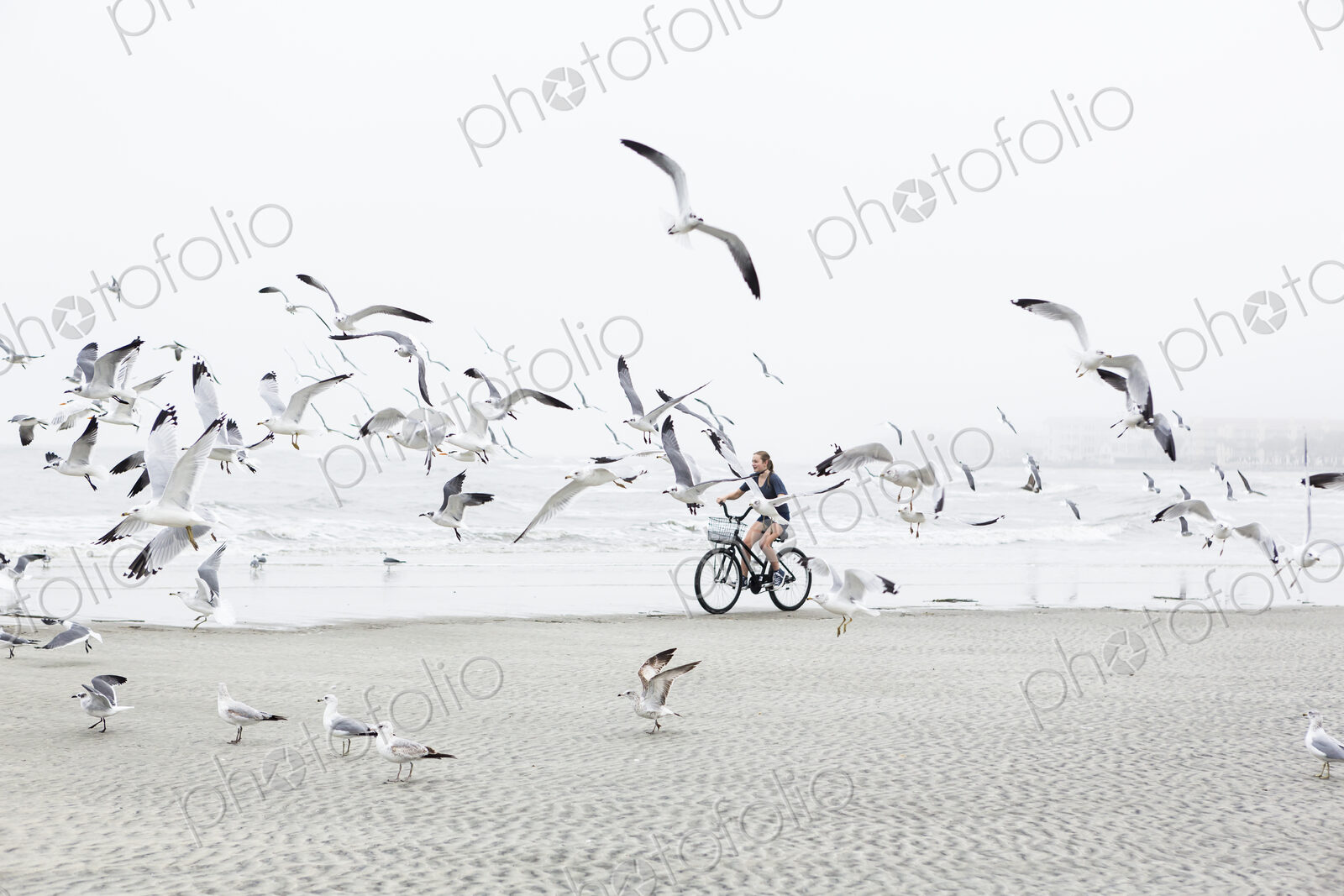 Teen girl biking on sandy beach by the ocean, St. Simon’s Island, Georgia