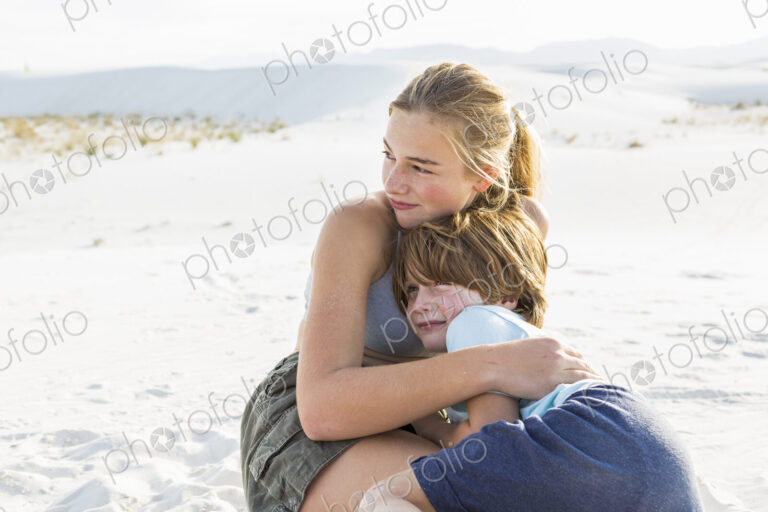 Teen girl embracing her brother, White Sands Nat'l Monument, NM