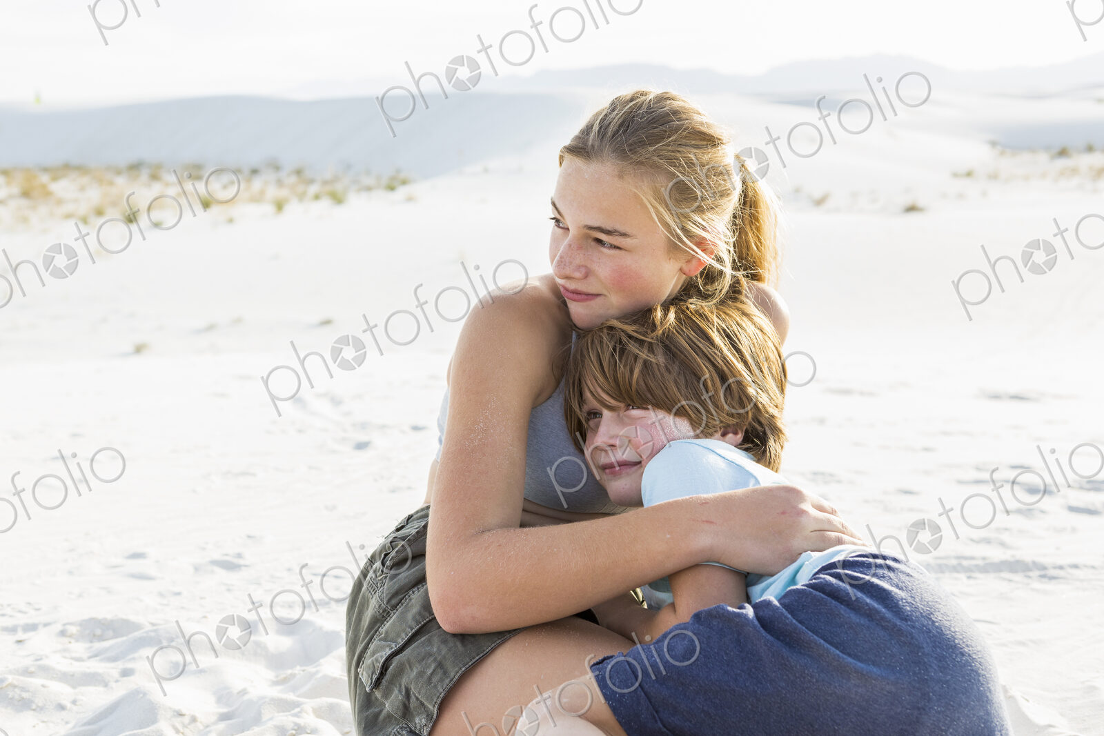 Teen girl embracing her brother, White Sands Nat’l Monument, NM