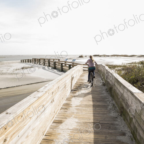 Teen girl on her bike crossing bridge to the beach, St. Simon's Island, Georgia Teen girl on her bike crossing bridge to the beach, St. Simon's Island, Georgia