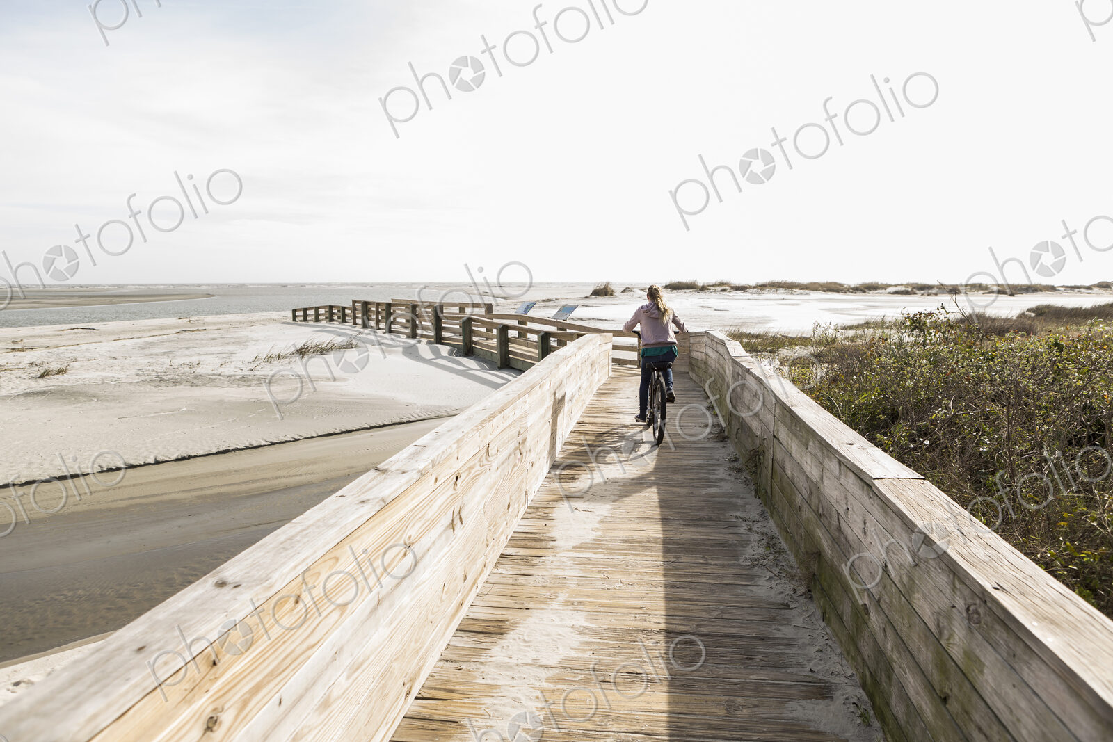 Teen girl on her bike crossing bridge to the beach, St. Simon’s Island, Georgia
