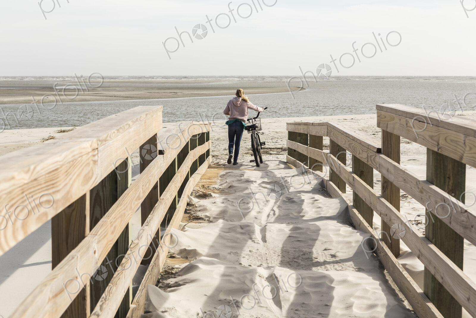 Teen girl on her bike crossing bridge to the beach, St. Simon’s Island, Georgia