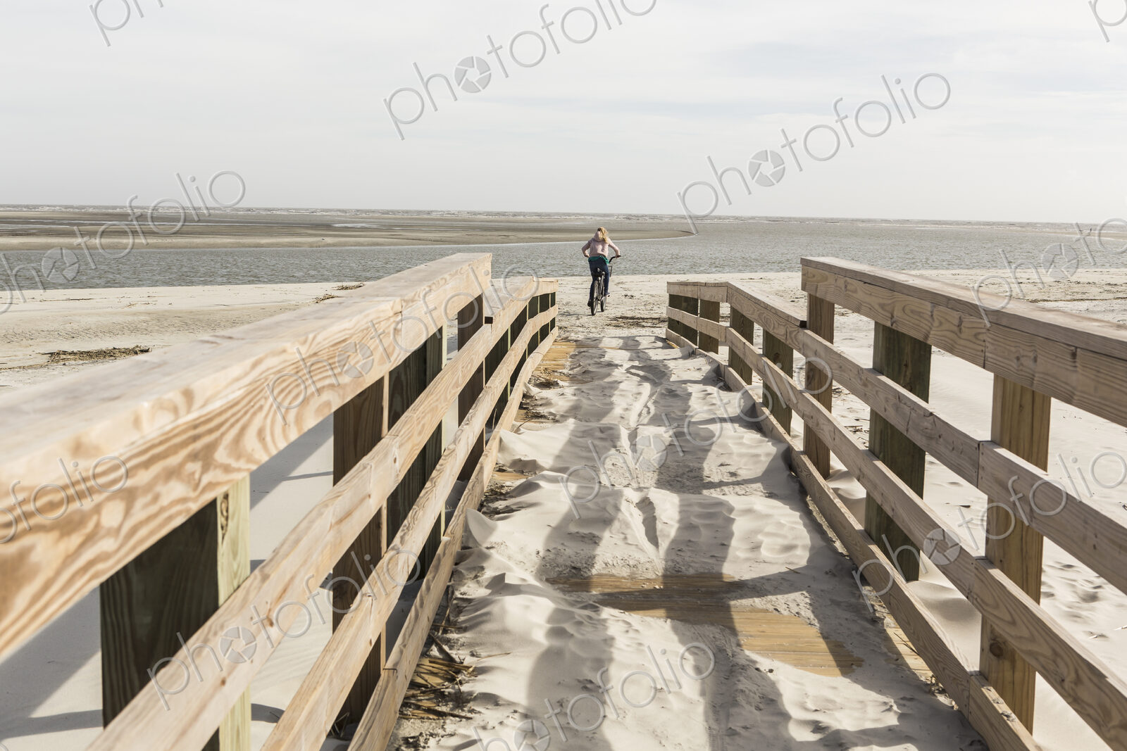 Teen girl on her bike crossing bridge to the beach, St. Simon’s Island, Georgia
