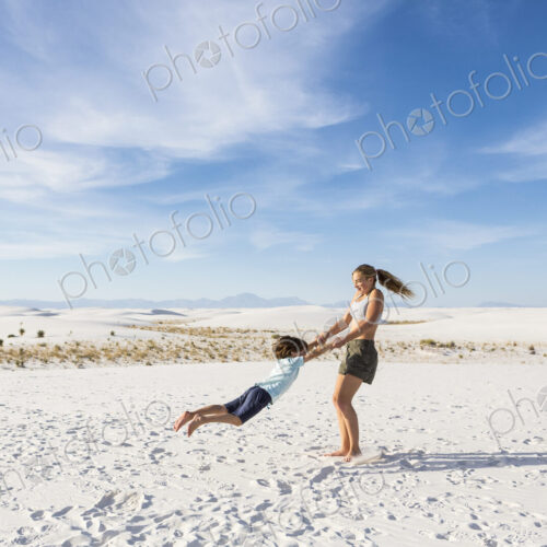 Teen girl swinging her 6 year old brother in sand, White Sands Nat'l Monument, NM Teen girl swinging her 6 year old brother in sand, White Sands Nat'l Monument, NM