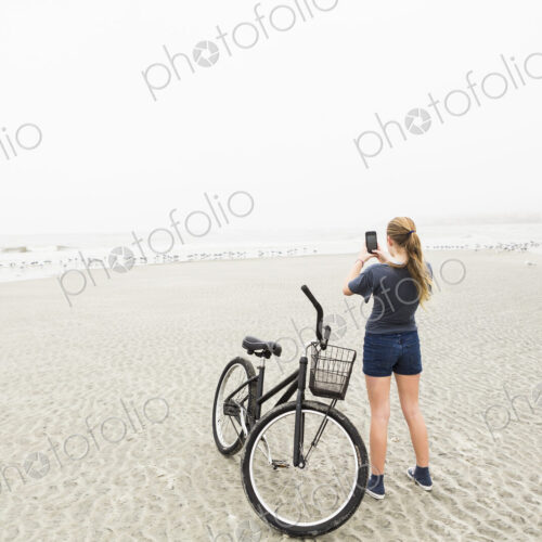 Teen girl talking pictures with smart phone at the beach, St. Simon's Island, Georgia