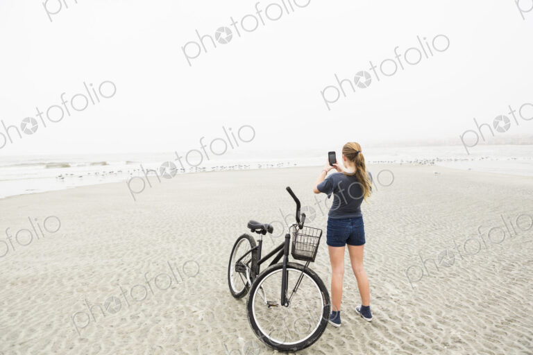 Teen girl talking pictures with smart phone at the beach, St. Simon's Island, Georgia