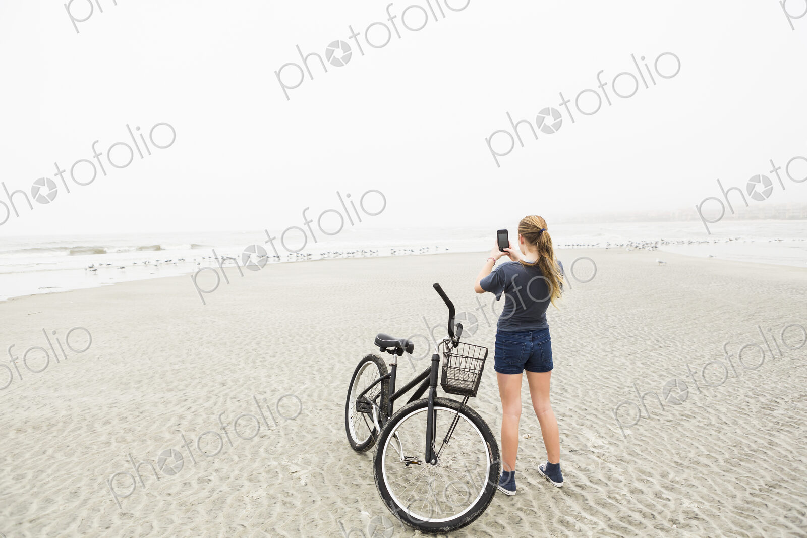 Teen girl talking pictures with smart phone at the beach, St. Simon’s Island, Georgia