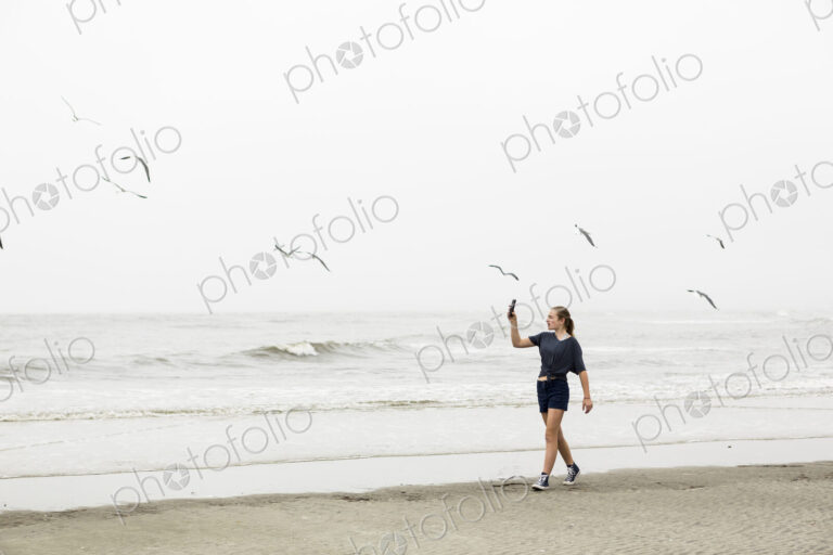 Teen girl talking pictures with smart phone at the beach, St. Simon's Island, Georgia