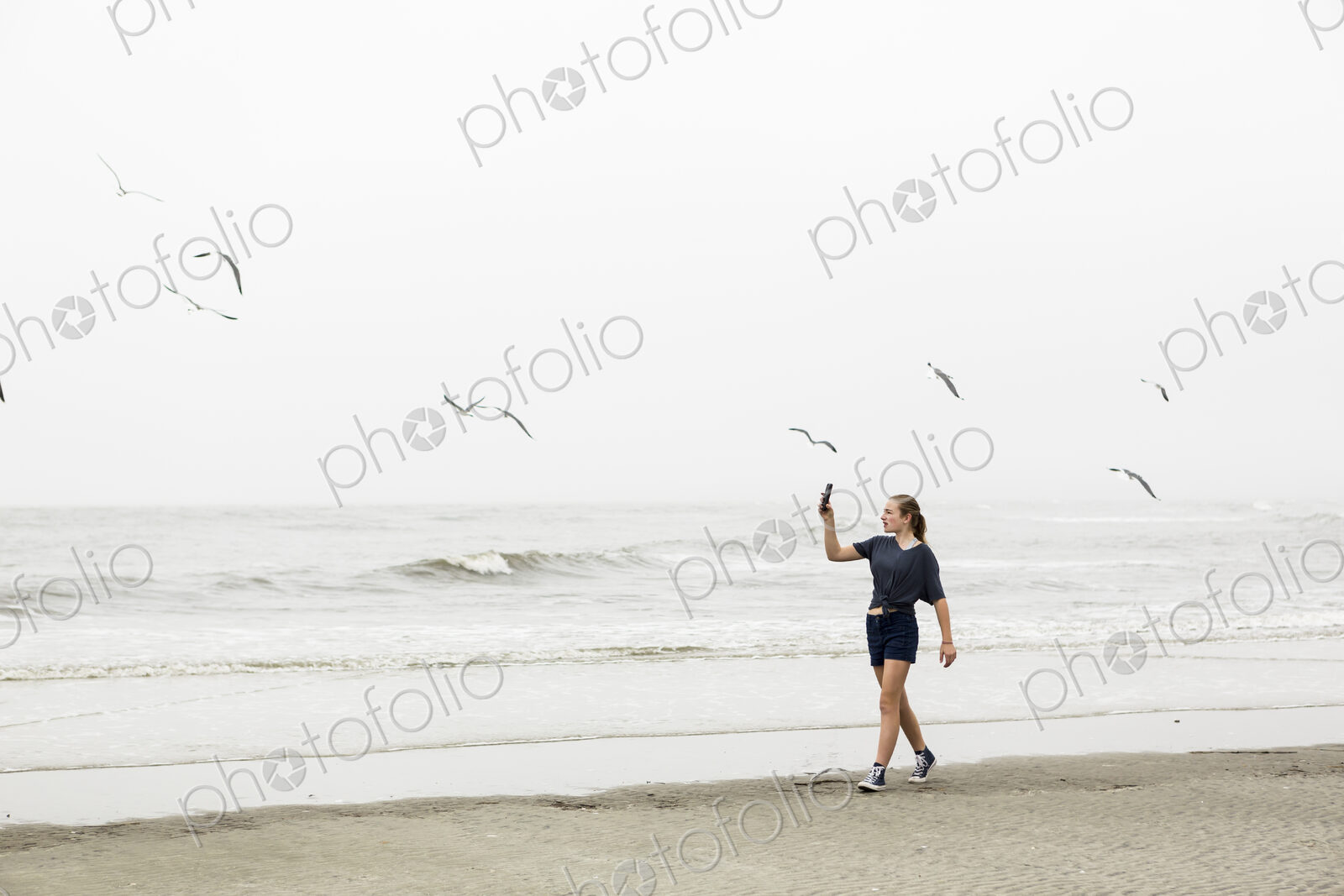 Teen girl talking pictures with smart phone at the beach, St. Simon’s Island, Georgia