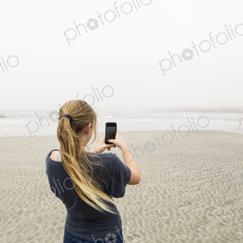 Teen girl talking pictures with smart phone at the beach, St. Simon's Island, Georgia
