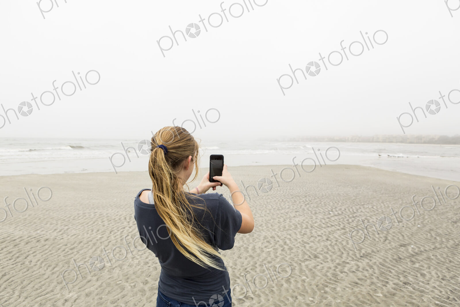 Teen girl talking pictures with smart phone at the beach, St. Simon’s Island, Georgia