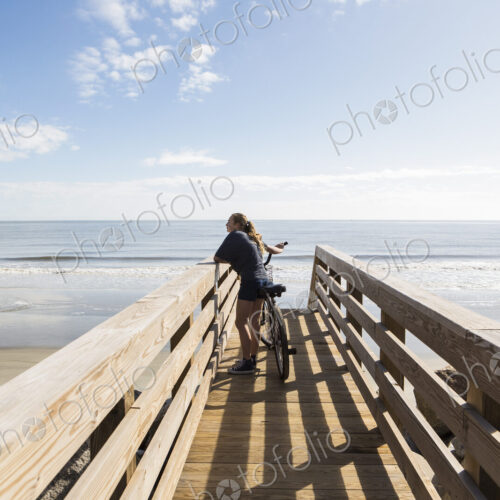 Teenage girl on wooden bridge by the beach, with her bike Teenage girl on wooden bridge by the beach, with her bike