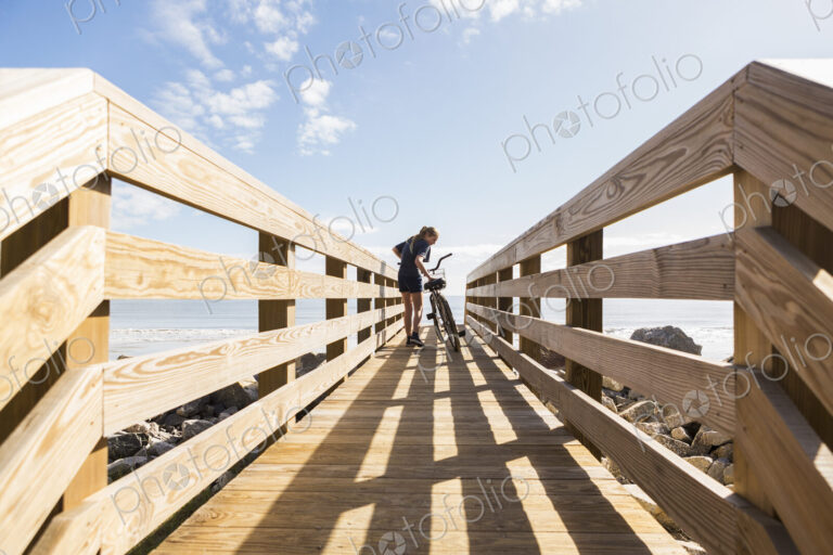 Teenage girl on wooden bridge with her bike