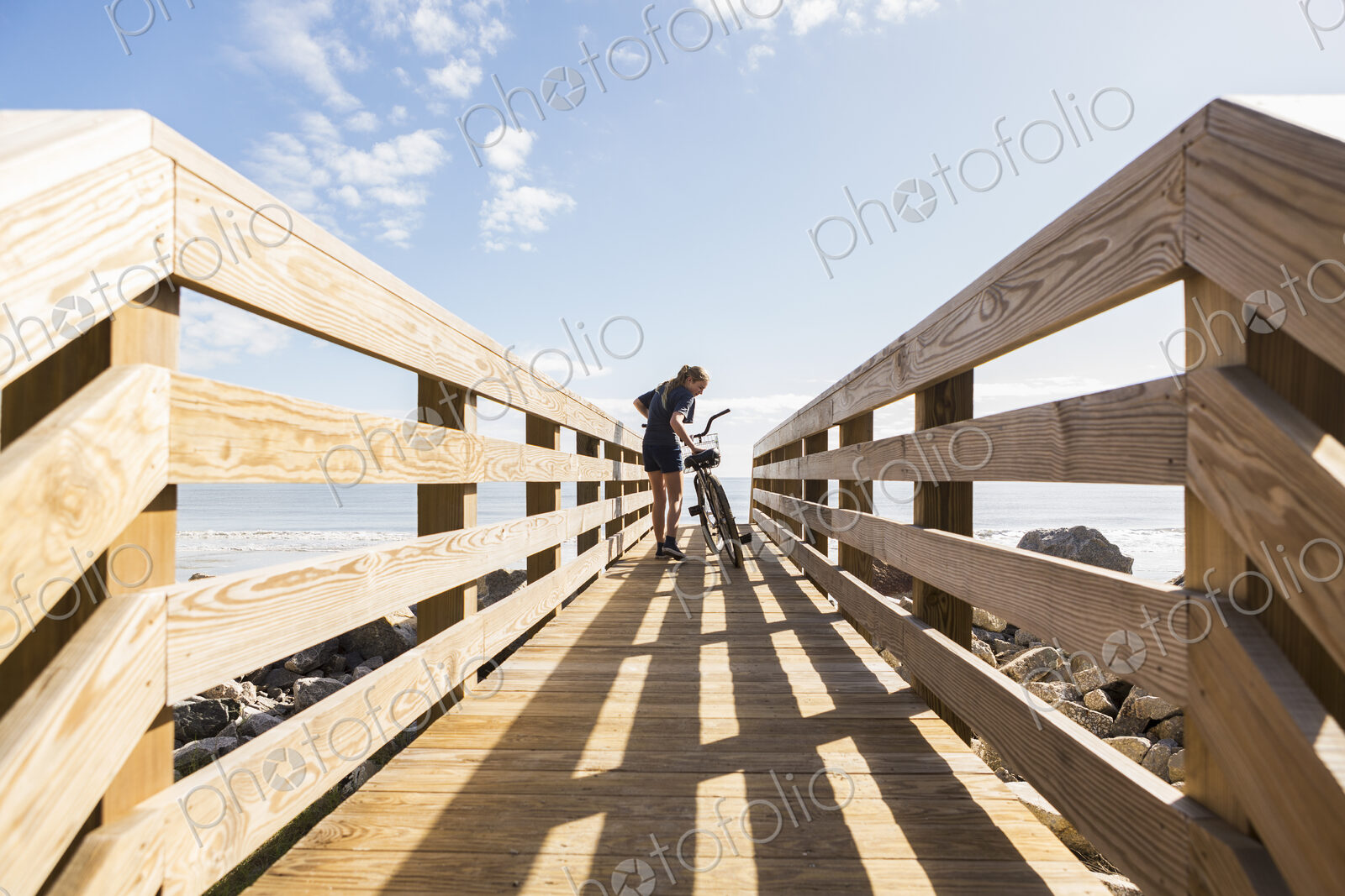 Teenage girl on wooden bridge with her bike