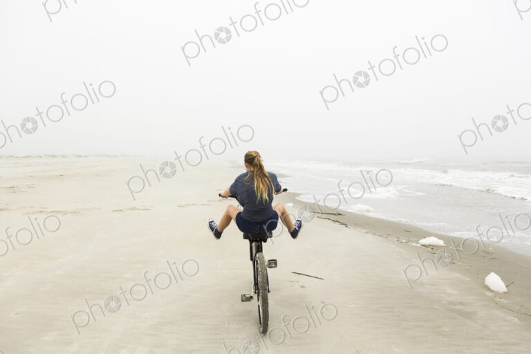 Teenage girl riding a bike on sand at the beach, St. Simon's Island Georgia