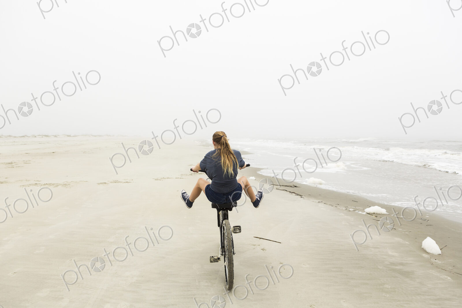 Teenage girl riding a bike on sand at the beach, St. Simon’s Island Georgia