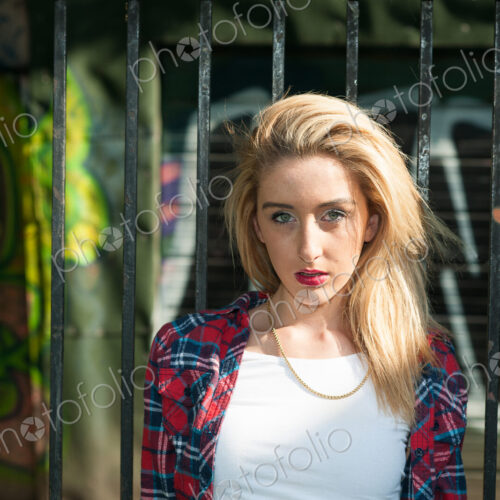 Teenage girl standing in front of graffiti on wall. Teenage girl standing in front of graffiti on wall.