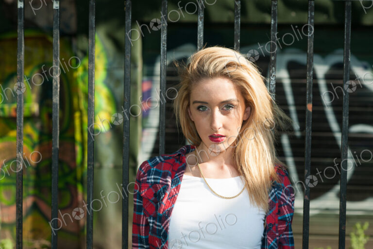 Teenage girl standing in front of graffiti on wall.