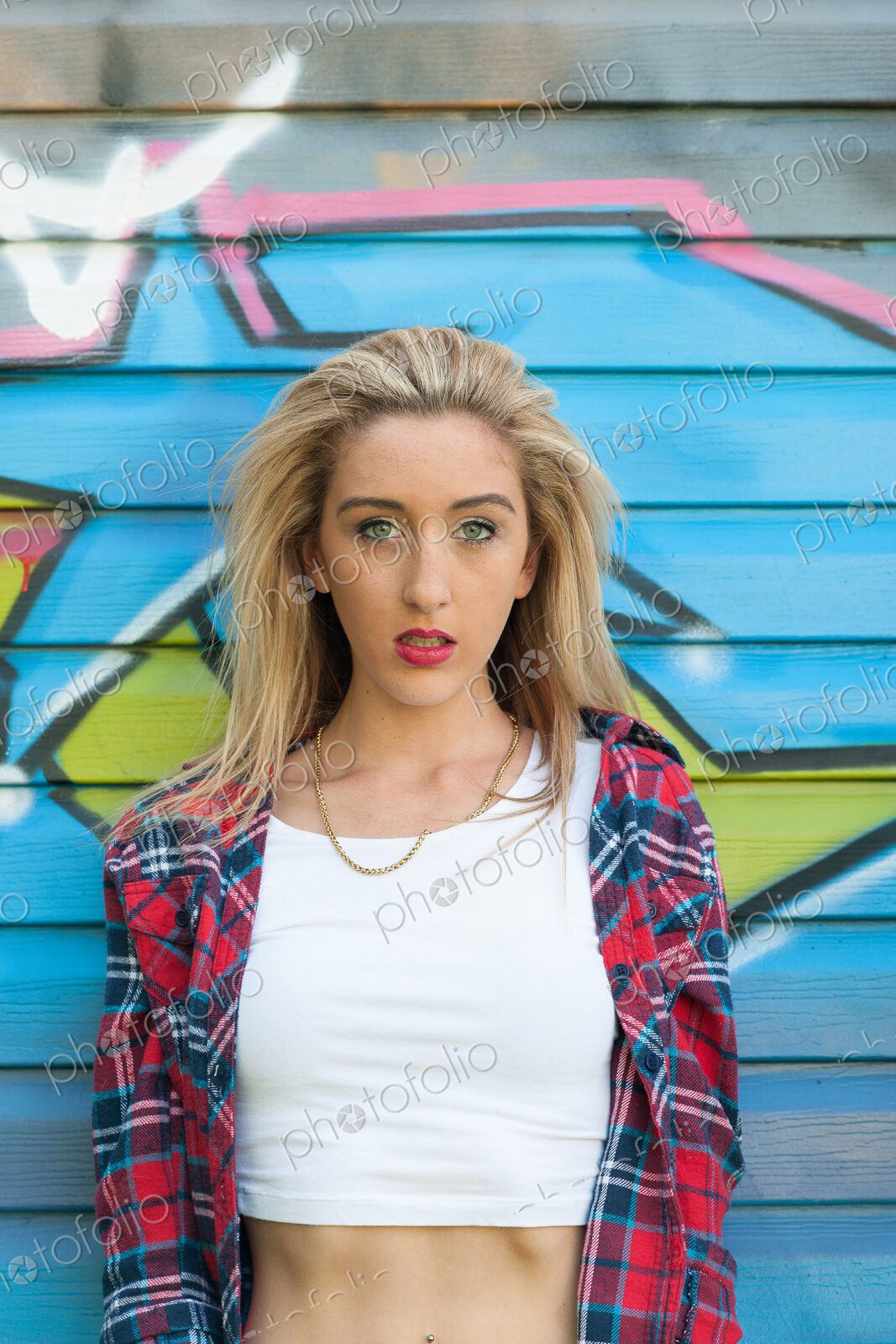 Teenage girl standing in front of graffiti on wall.