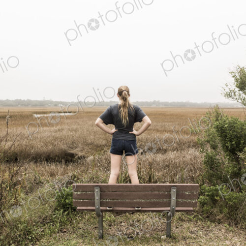 Teenage girl standing on a bench looking out over marshes, St. Simon's Island, Georgia